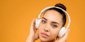 Kosmetyczne gadżety z TikToka – które akcesoria beauty są warte swojej ceny Kobieta w słuchawkach na pomarańczowym tle jako gadżet beauty z TikToka